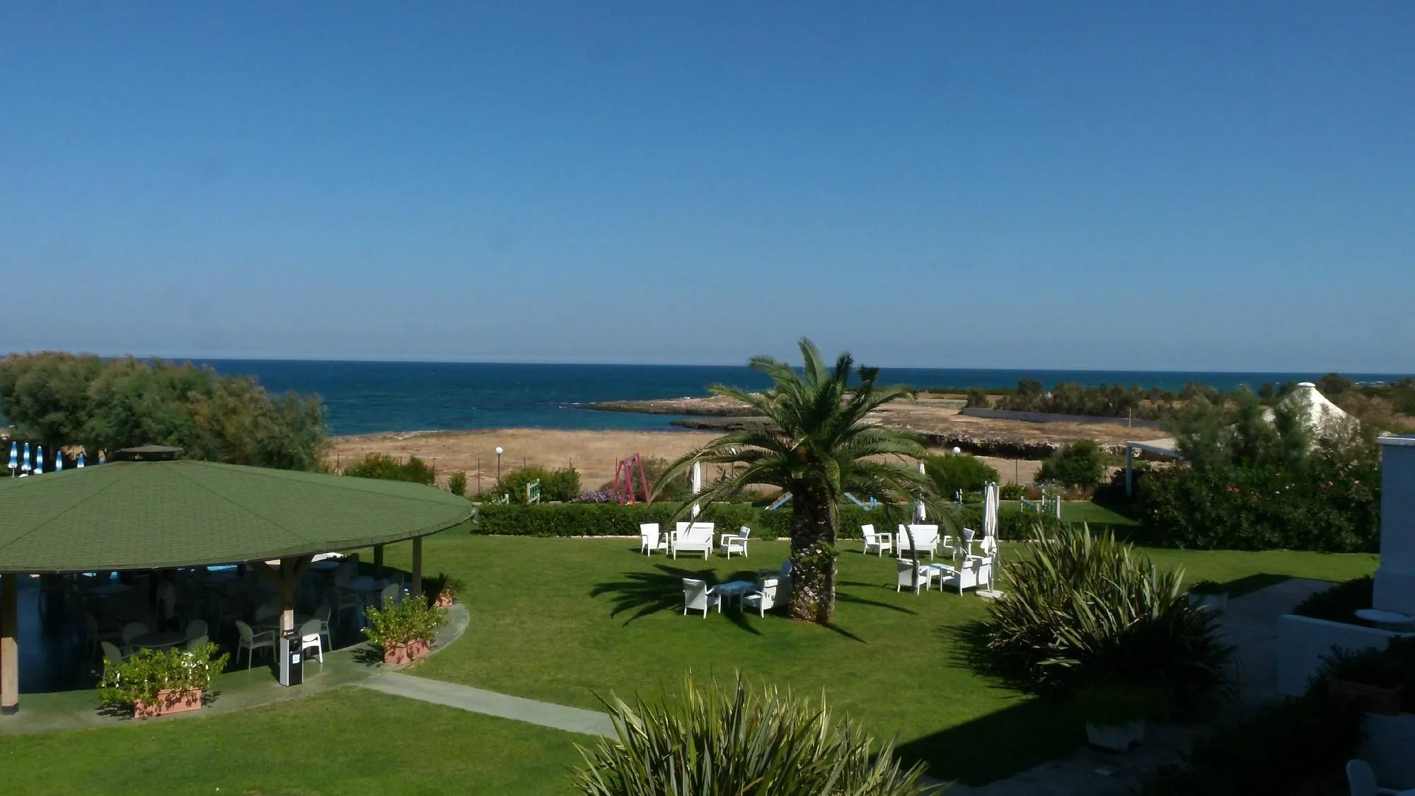 Panorama del giardino con gazebo verde, palma e poltrone bianche affacciato sul mare