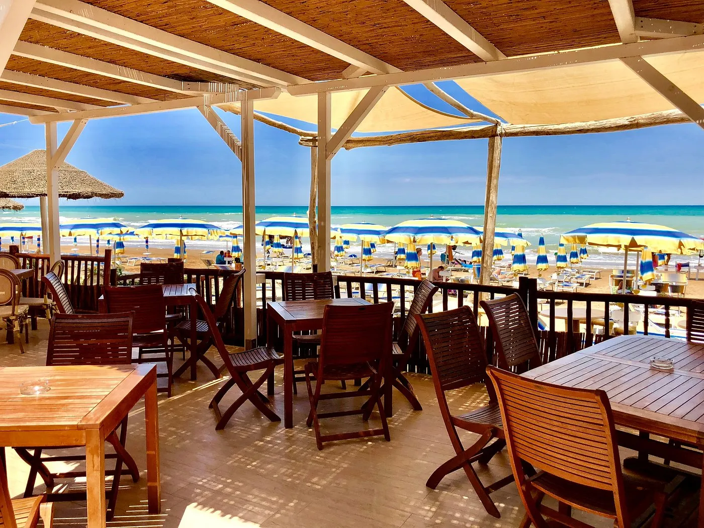 Terrazza ristorante in legno con vista sul mare e ombrelloni colorati