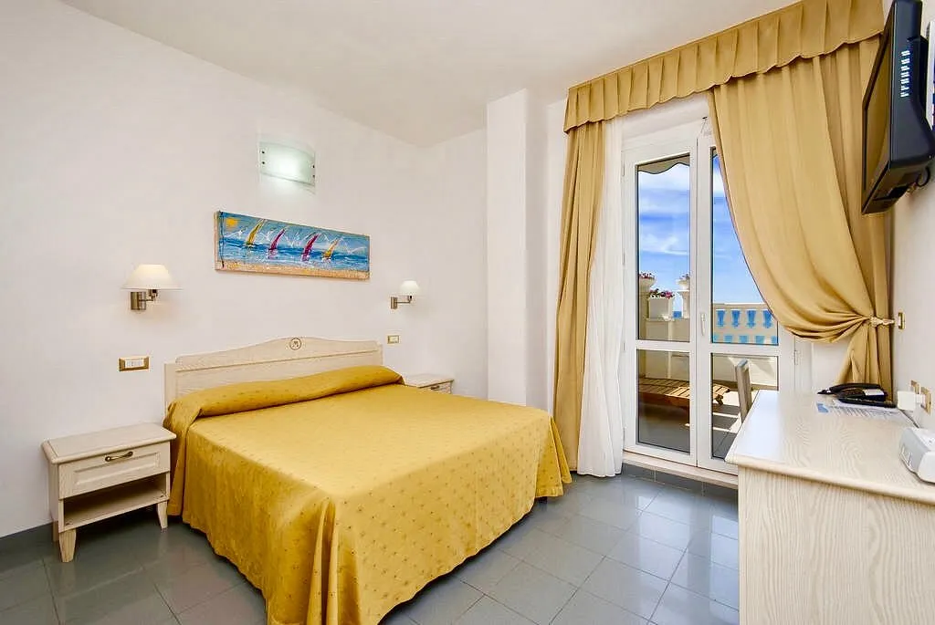 Camera con copriletto giallo, balcone vista mare e TV