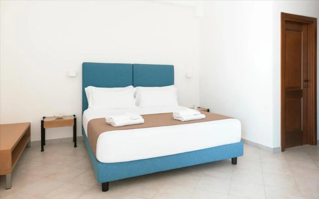 Camera con letto matrimoniale, testiera azzurra e pavimento chiaro