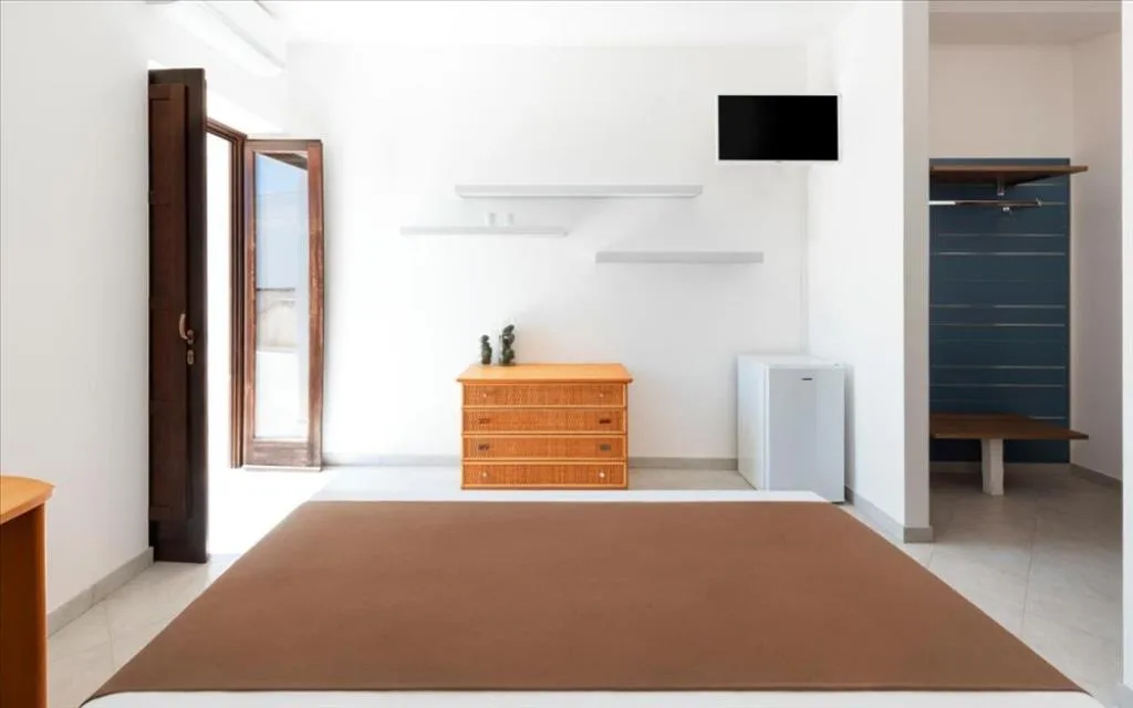 Camera moderna con cassettiera in legno, mini frigo e TV a parete