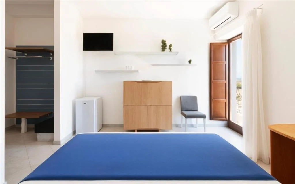 Camera con letto blu, cassettiera in legno e finestra con vista mare