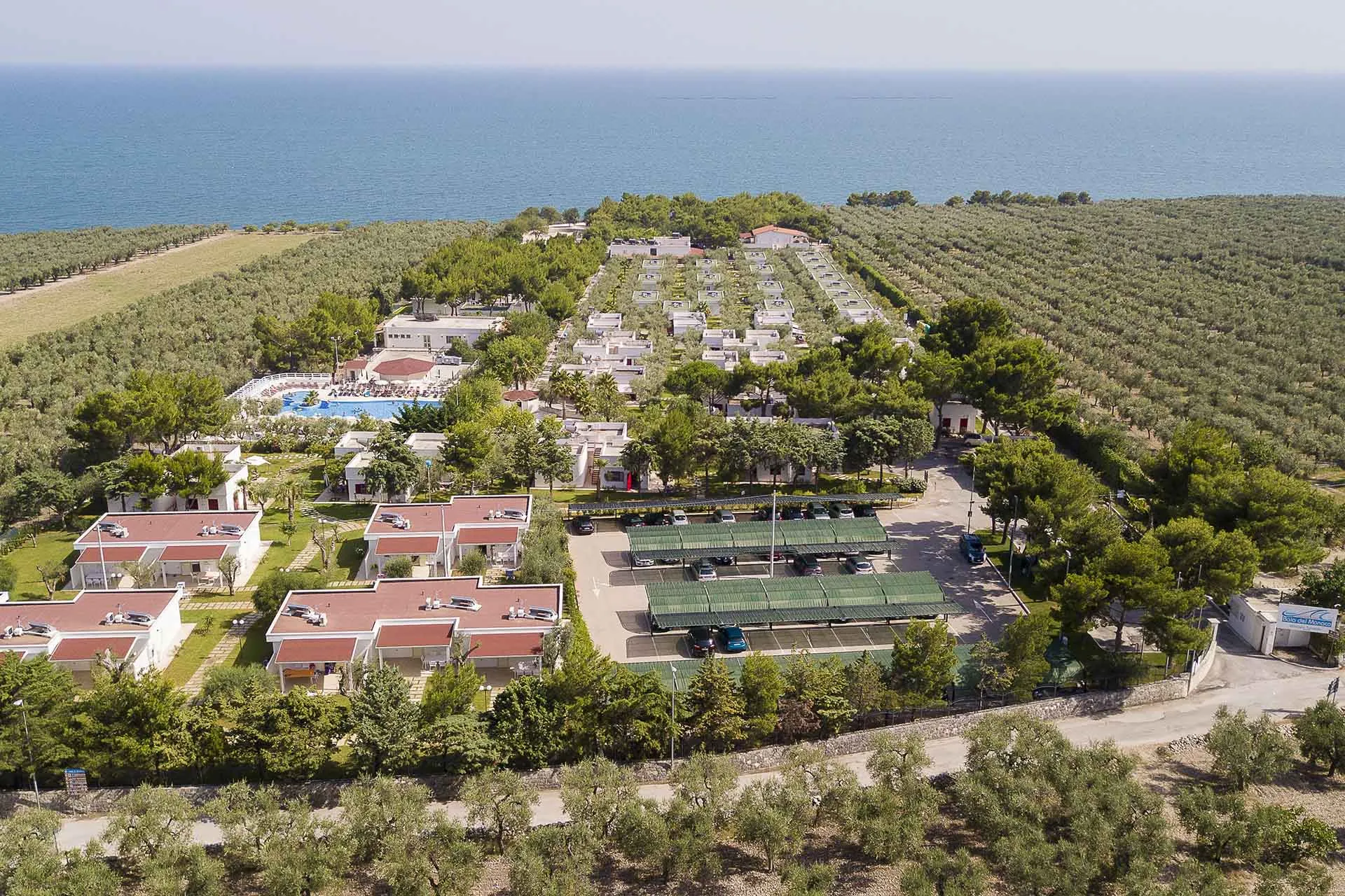 Panoramica aerea del villaggio con bungalow, piscina e parcheggio affacciato sul mare