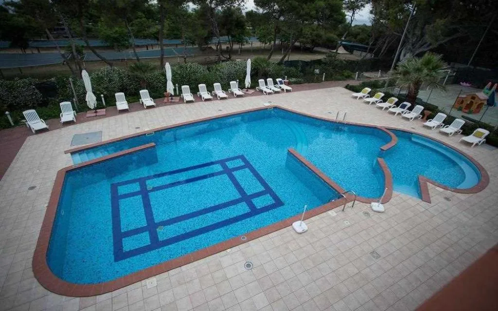 Piscina esterna vista dall'alto con lettini e ombrelloni immersi nella pineta
