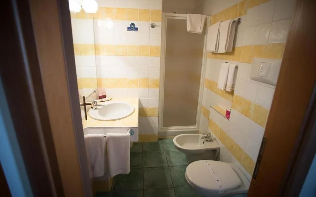 Bagno con piastrelle gialle e bianche, lavabo, bidet, WC e doccia