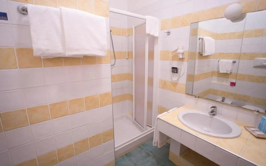 Bagno con doccia, lavabo, specchio, asciugacapelli e piastrelle gialle e bianche