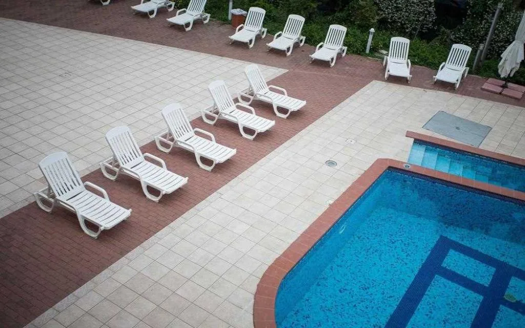 Bordo piscina con lettini bianchi in fila e pavimentazione in cotto