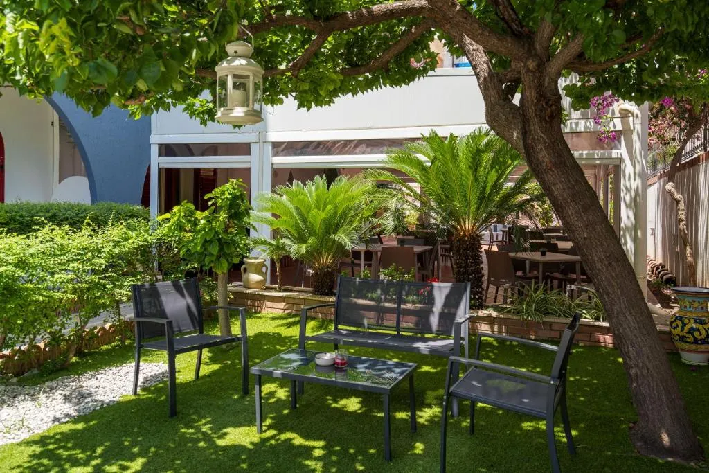 Angolo giardino ombreggiato con poltrone, tavolino e alberi