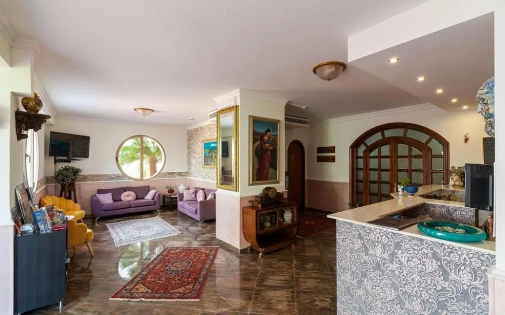 Ampia hall con divani viola, poltrona gialla, tappeti e reception