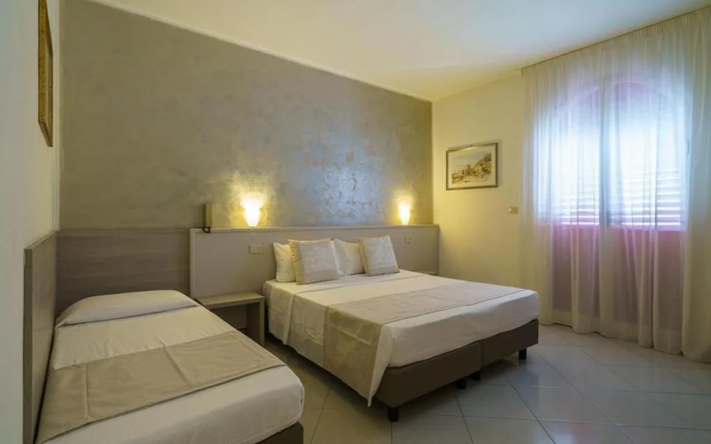 Camera con letto matrimoniale, letto singolo e parete decorativa color sabbia