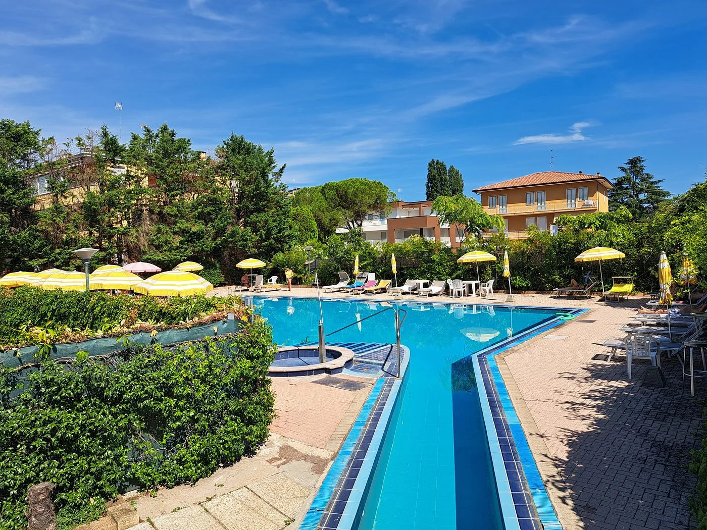Piscina esterna con ombrelloni colorati immersa nel verde del giardino