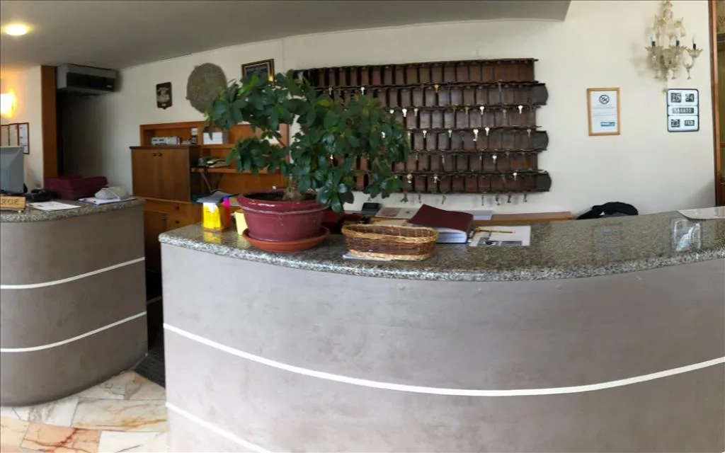 Reception dell'hotel con bancone in marmo e bacheca portachiavi in legno