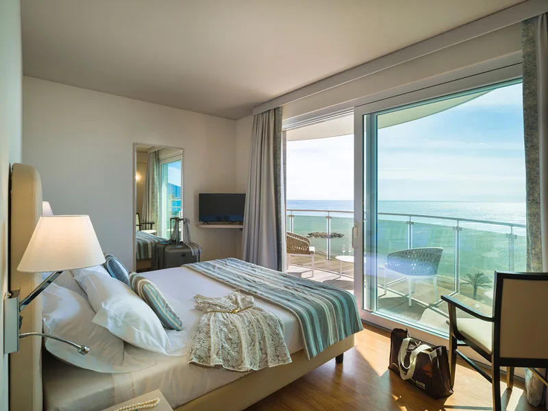 Camera luminosa con letto matrimoniale, ampia vetrata e balcone vista mare