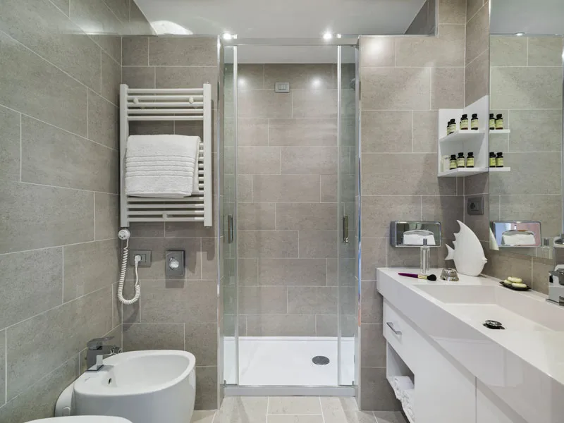 Bagno moderno con doccia, bidet, lavabo e rivestimenti grigi