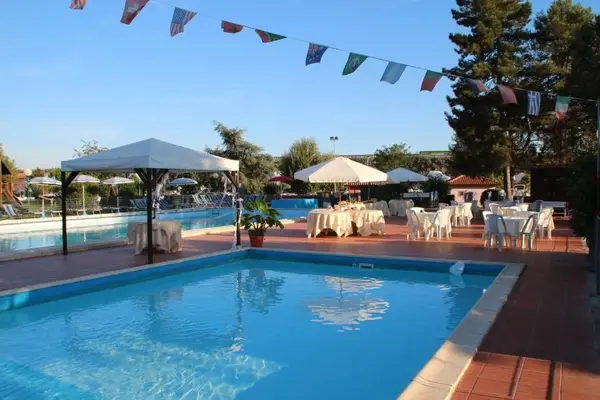 Piscina con tavoli apparecchiati, gazebo bianco e bandiere internazionali decorative