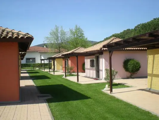 Bungalow colorati con tetti in tegole, portici in legno e prato verde curato