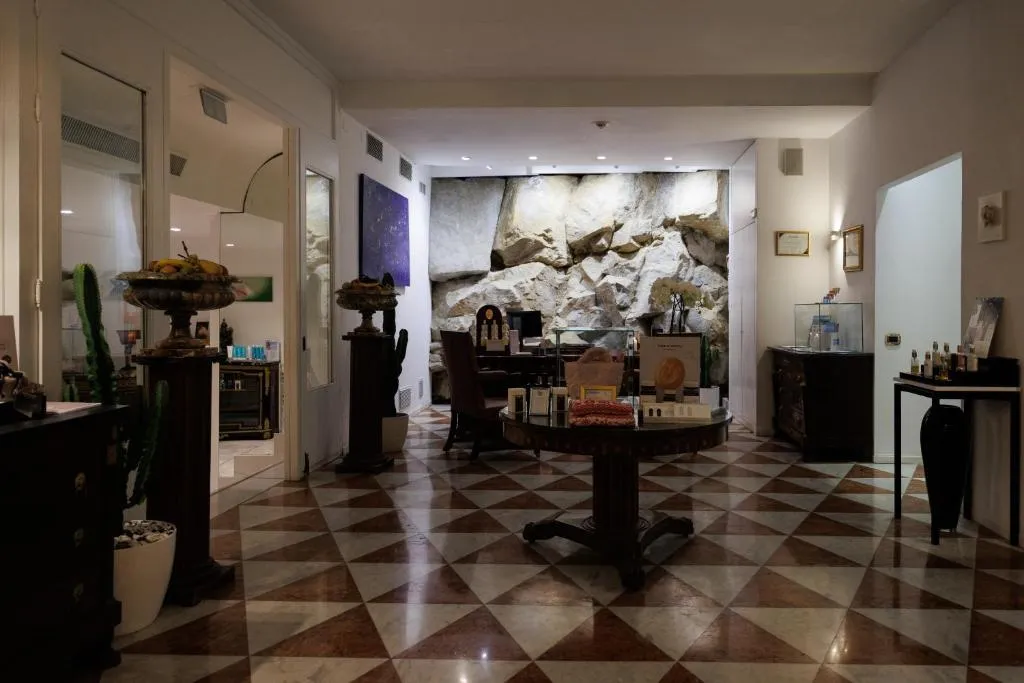 Reception della spa con pavimento a scacchi, parete in roccia e prodotti per il benessere