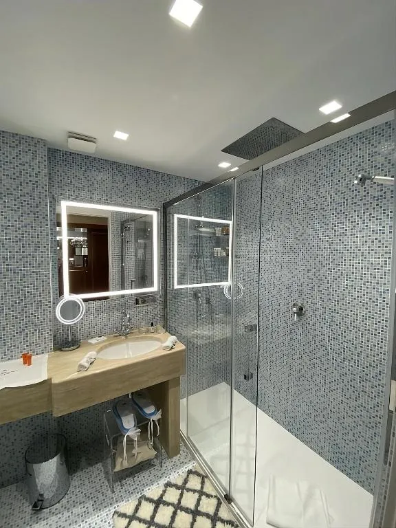 Bagno moderno con doccia in vetro e rivestimento a mosaico grigio
