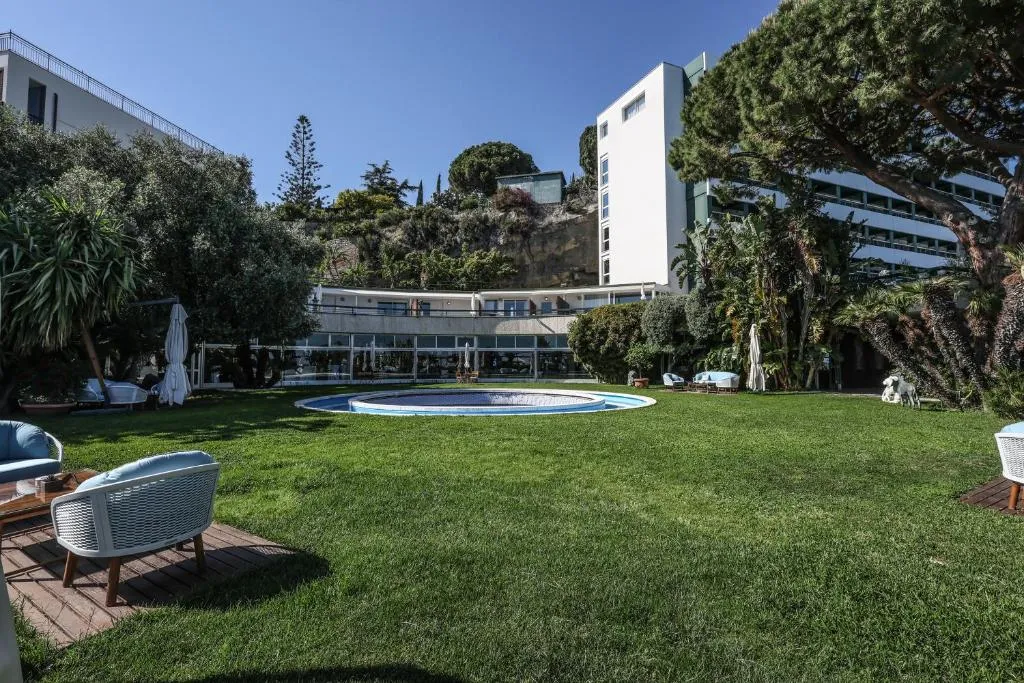 Giardino con prato verde, piscina circolare e poltrone all'aperto