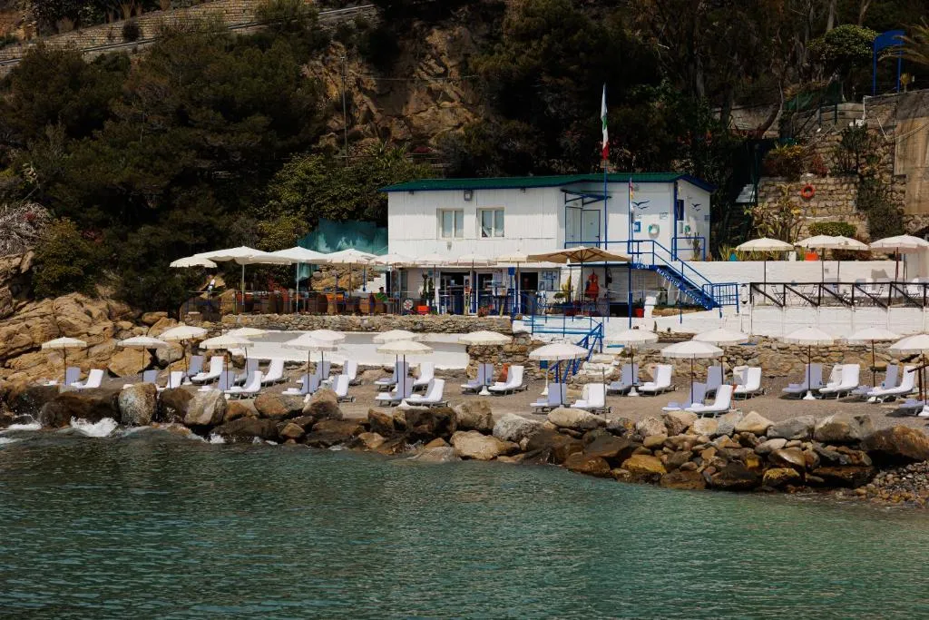 Stabilimento balneare con lettini bianchi, ombrelloni e mare cristallino