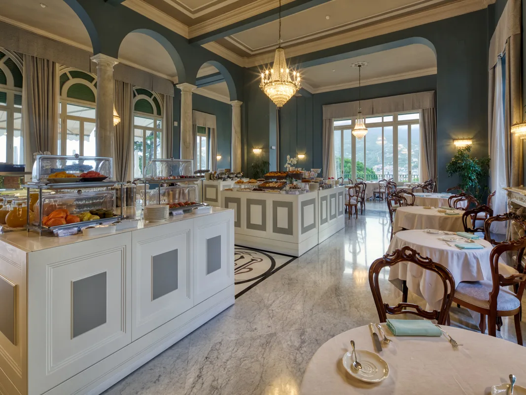 Sala colazione con buffet, soffitti decorati, lampadari e pareti verde acqua