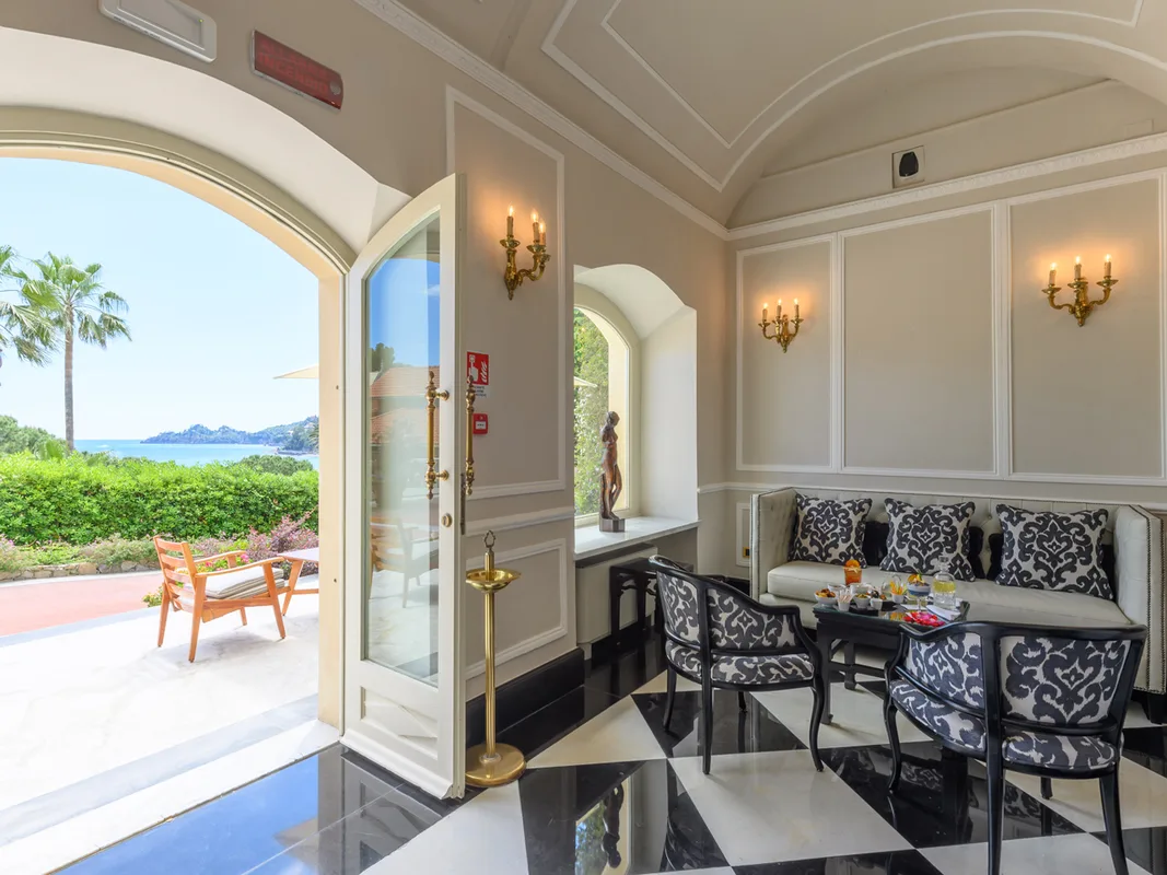 Salottino elegante con pavimento a scacchi e accesso alla terrazza con vista mare