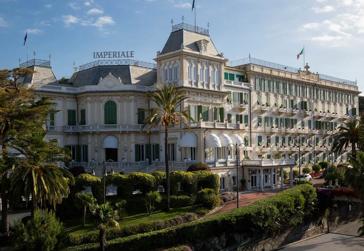Facciata dell'Hotel Imperiale con giardini curati, palme e bandiere