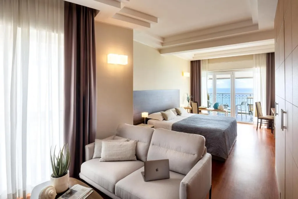 Camera spaziosa con divano, letto matrimoniale e balcone vista mare