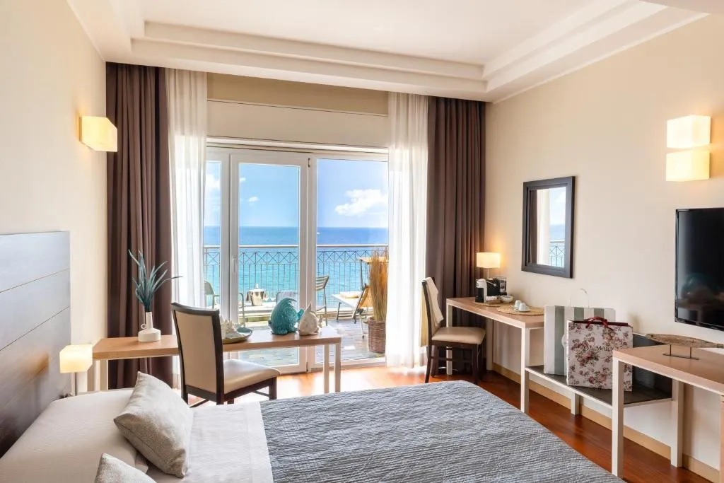 Camera moderna con scrivanie, TV e balcone affacciato sul mare
