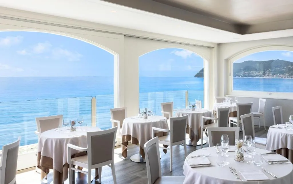 Sala ristorante luminosa con grandi finestre ad arco e vista panoramica sul mare