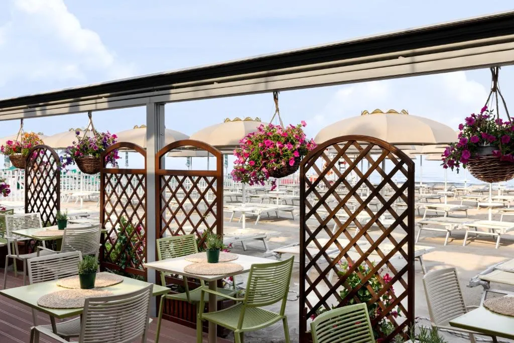 Terrazza con tavoli, fiori e vista sulla spiaggia attrezzata