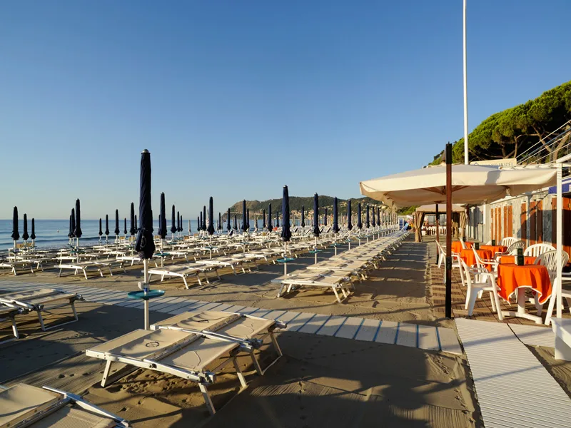 Spiaggia attrezzata con lettini e ombrelloni chiusi al sole del mattino