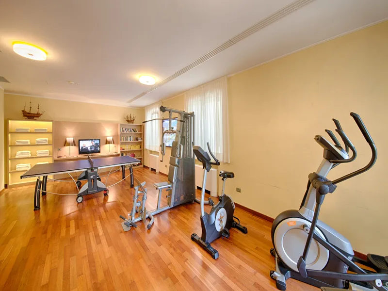 Sala fitness con tavolo da ping pong, cyclette ed ellittica