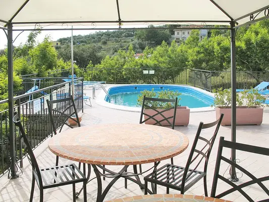 Terrazza con gazebo, tavolo rotondo e sedie in ferro affacciata sulla piscina e colline circostanti