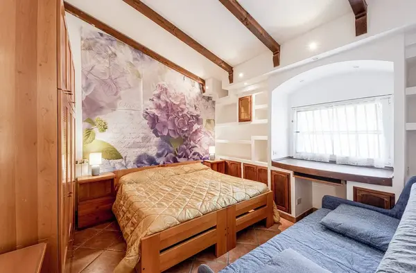 Camera da letto matrimoniale con parete decorata a fiori, travi in legno e divano blu