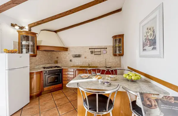 Cucina in legno con piano cottura, forno e tavolo con colazione e frutta