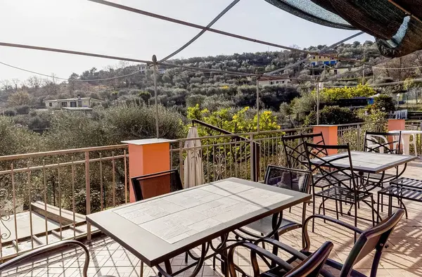 Terrazza con tavoli e sedie in ferro affacciata sulle colline con uliveti