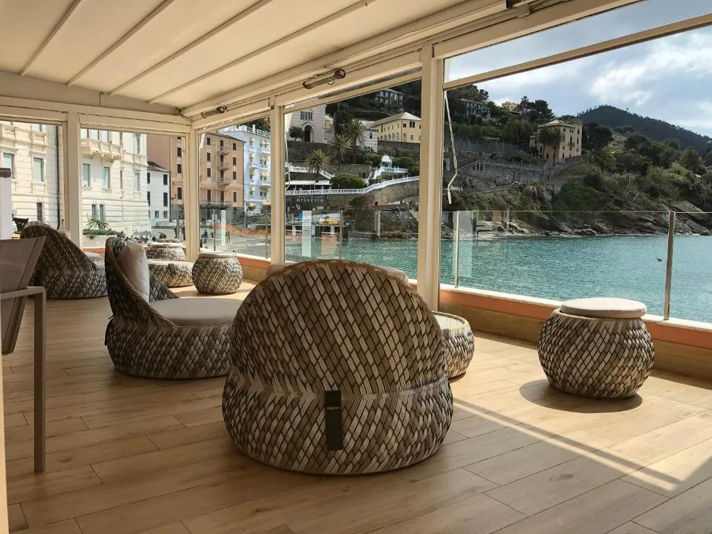 Lounge con poltrone in vimini intrecciato e ampie vetrate con vista sulla baia