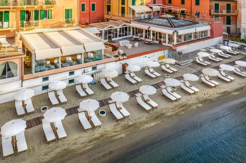 Vista aerea della spiaggia dell'hotel con lettini bianchi, ombrelloni e terrazza del ristorante