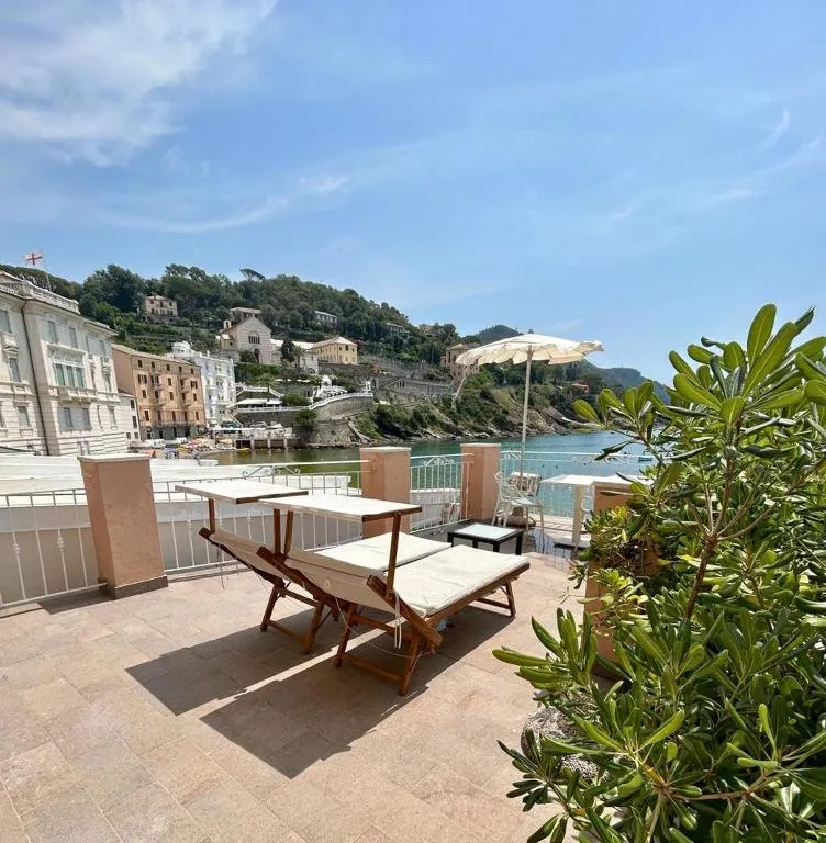 Terrazza con lettini prendisole e ombrellone affacciata sulla baia e la costa