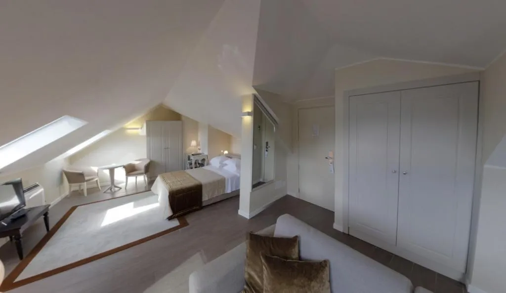 Camera mansardata elegante con letto, salottino e armadi a muro
