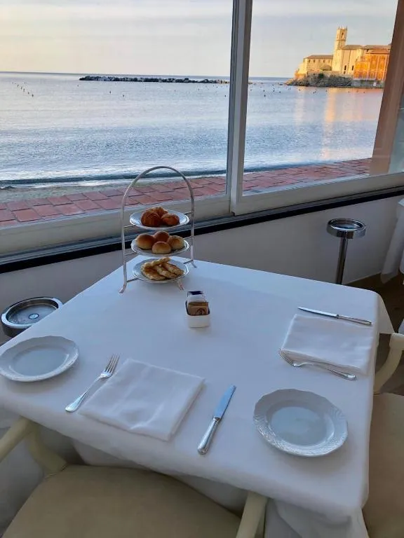 Tavolo per la colazione apparecchiato con vista sul mare e la chiesa al tramonto