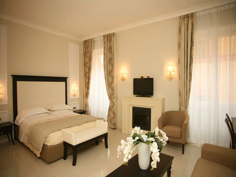 Ampia camera elegante con letto matrimoniale, camino, poltrone e fiori d'orchidea