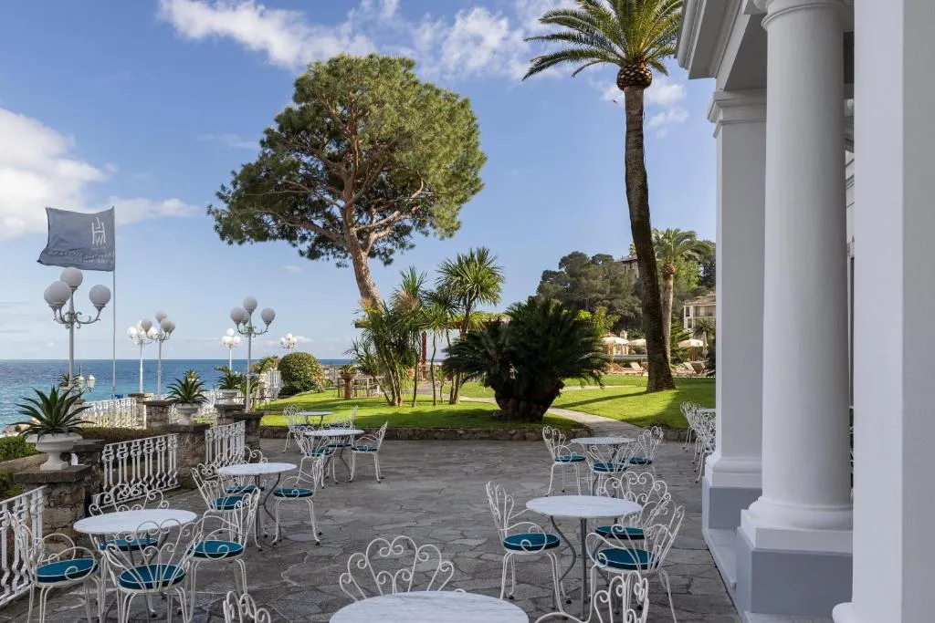 Terrazza esterna con tavolini in ferro battuto e sedie affacciata sul giardino e sul mare