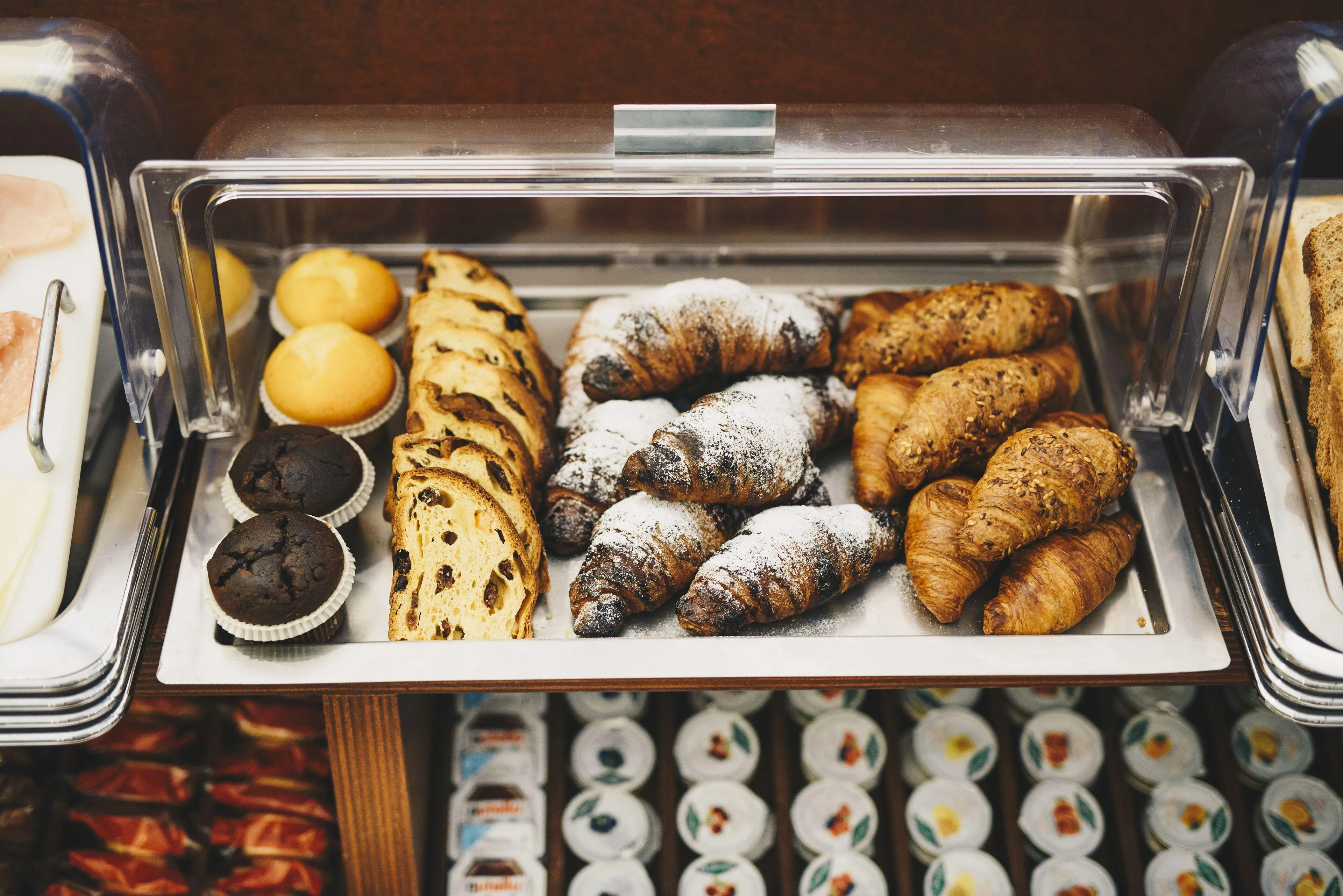 Vassoio con croissant, muffin e pane dolce esposti nel buffet della colazione