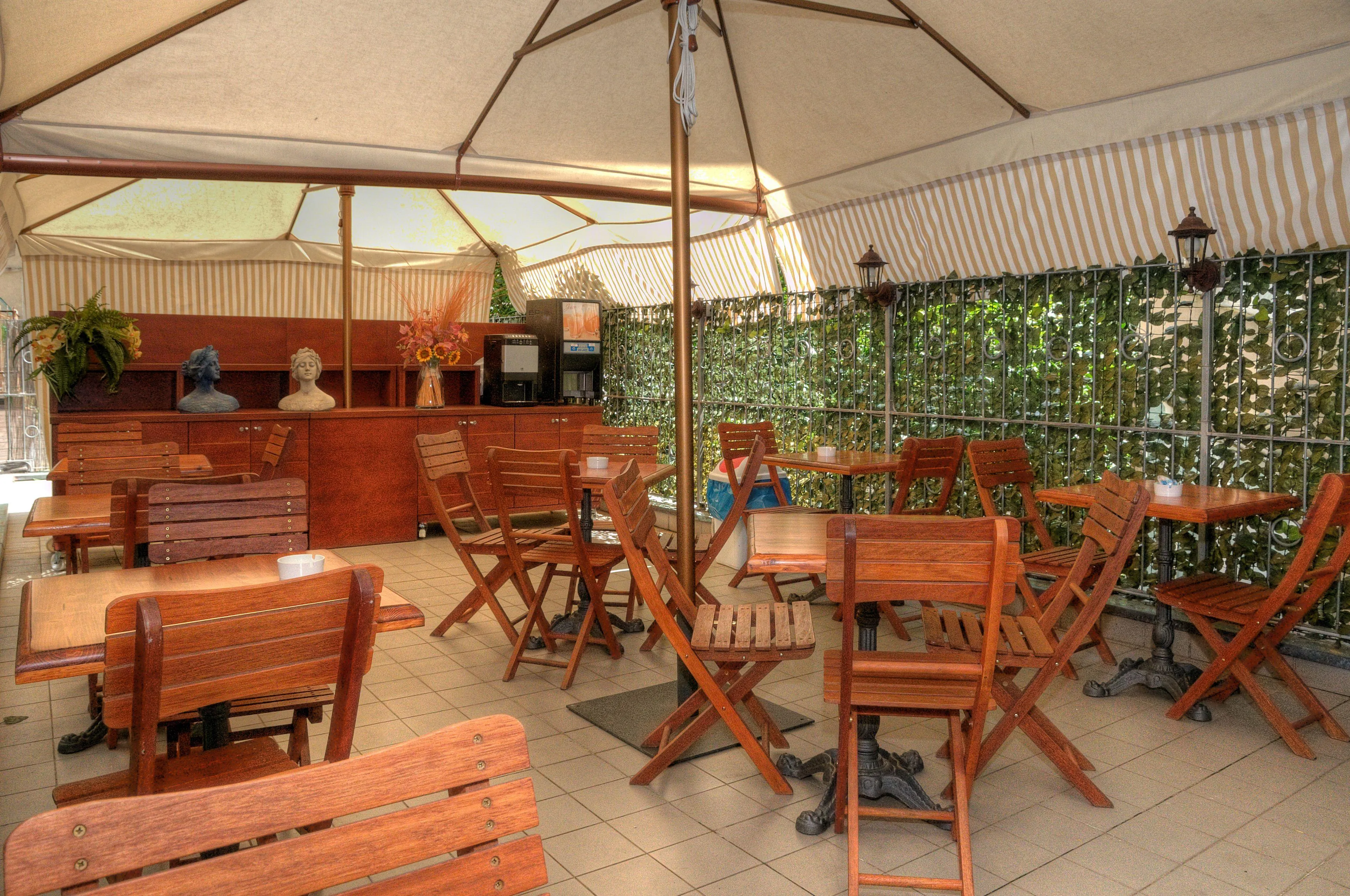 Terrazza esterna coperta con ombrelloni, tavoli e sedie in legno