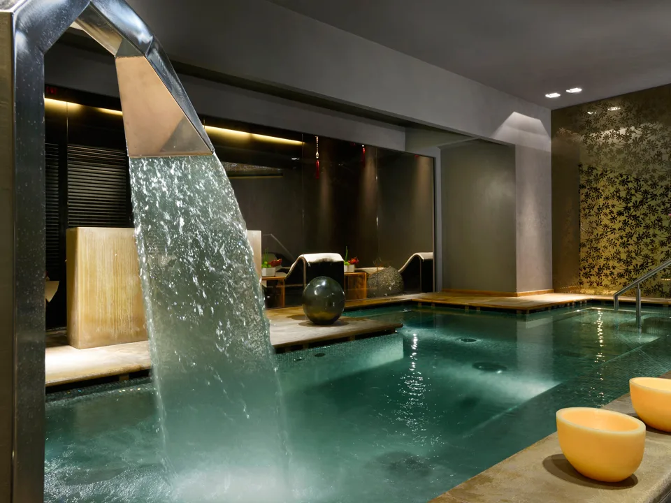Piscina interna della spa con cascata d'acqua e atmosfera rilassante