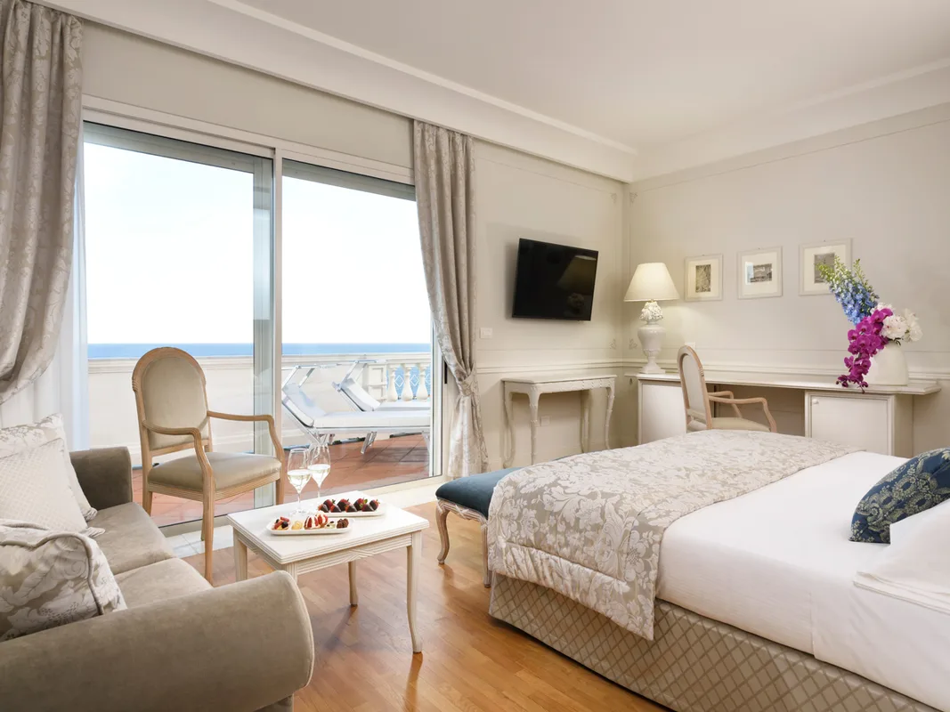 Camera elegante con salotto, parquet e ampia vetrata affacciata sulla terrazza vista mare