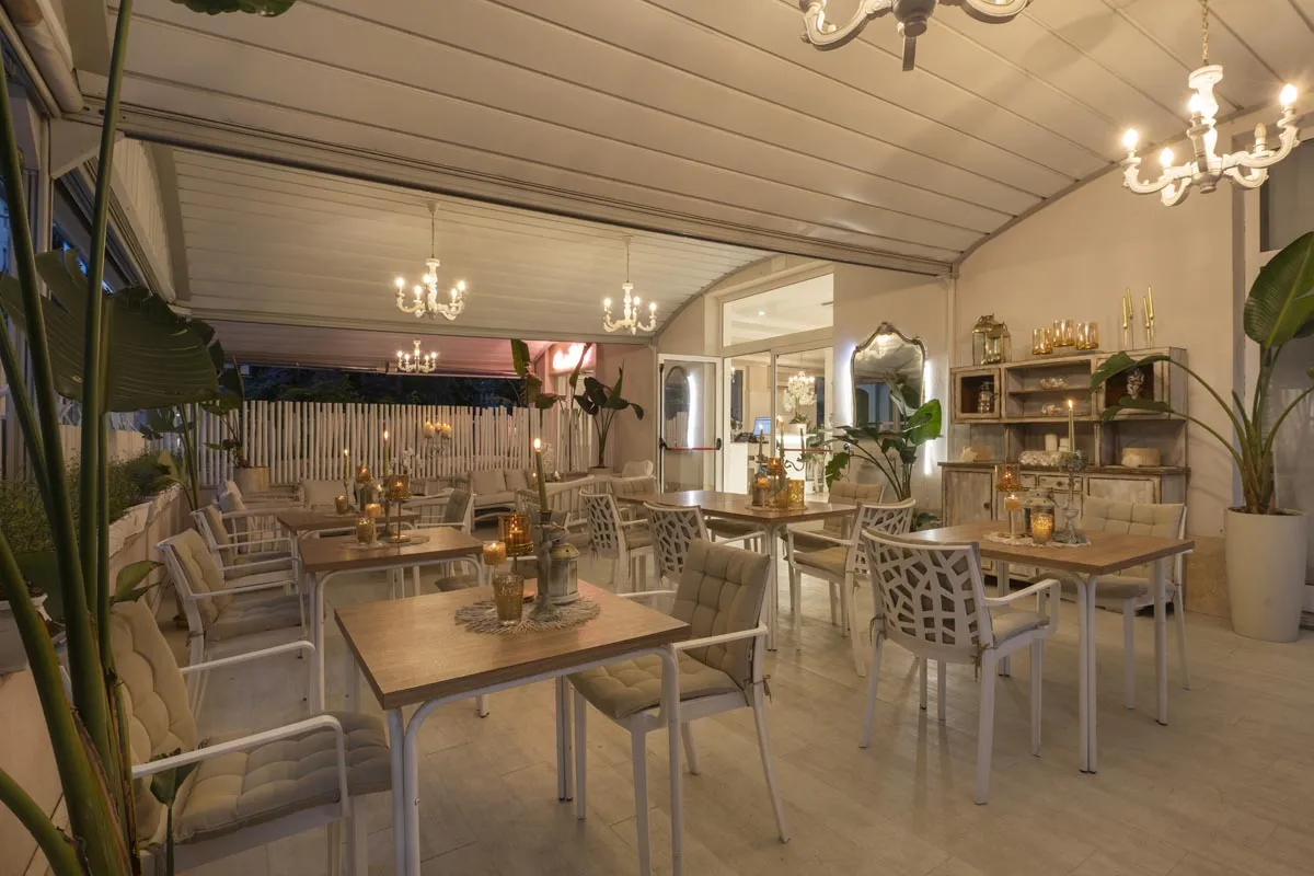 Ristorante interno con tavoli apparecchiati, lampadari e decorazioni shabby