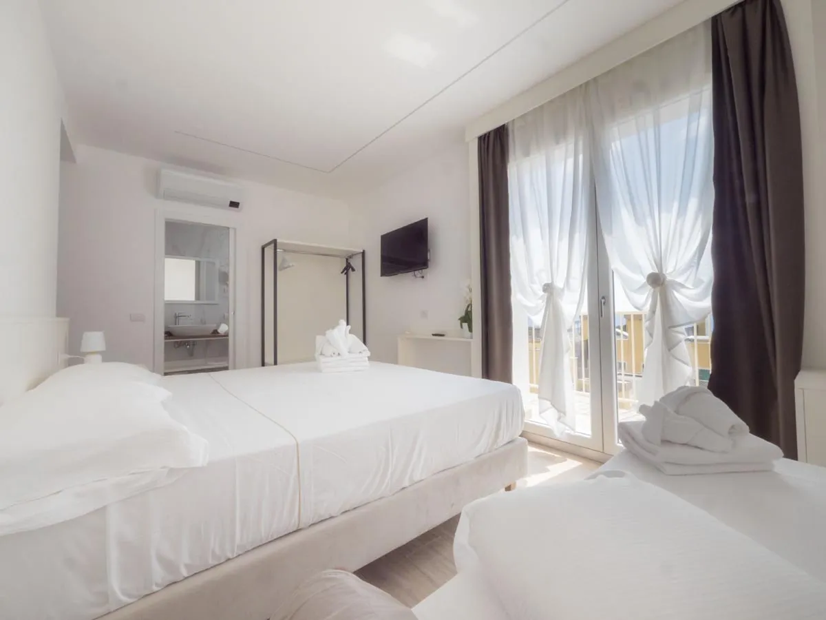 Camera con letto matrimoniale, TV e ampia finestra con tende